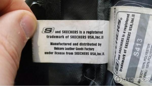 Бумажка на черном рюкзаке Skechers c коричневым смайликом