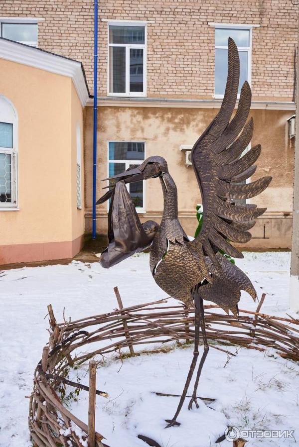 Скульптура аиста с младенцем